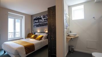 A bedroom with a bed, bedside table, and a large window.