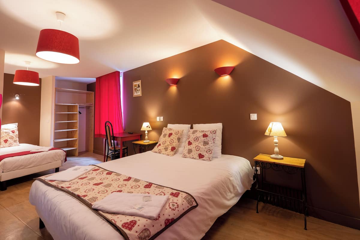 Ein Schlafzimmer mit einem großen Bett, zwei Nachttischen mit Lampen, einem Kleiderschrank und einem roten Vorhang.