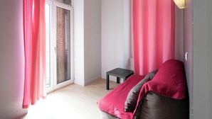 Een slaapkamer met een bed, een tafeltje en een raam met gordijnen.