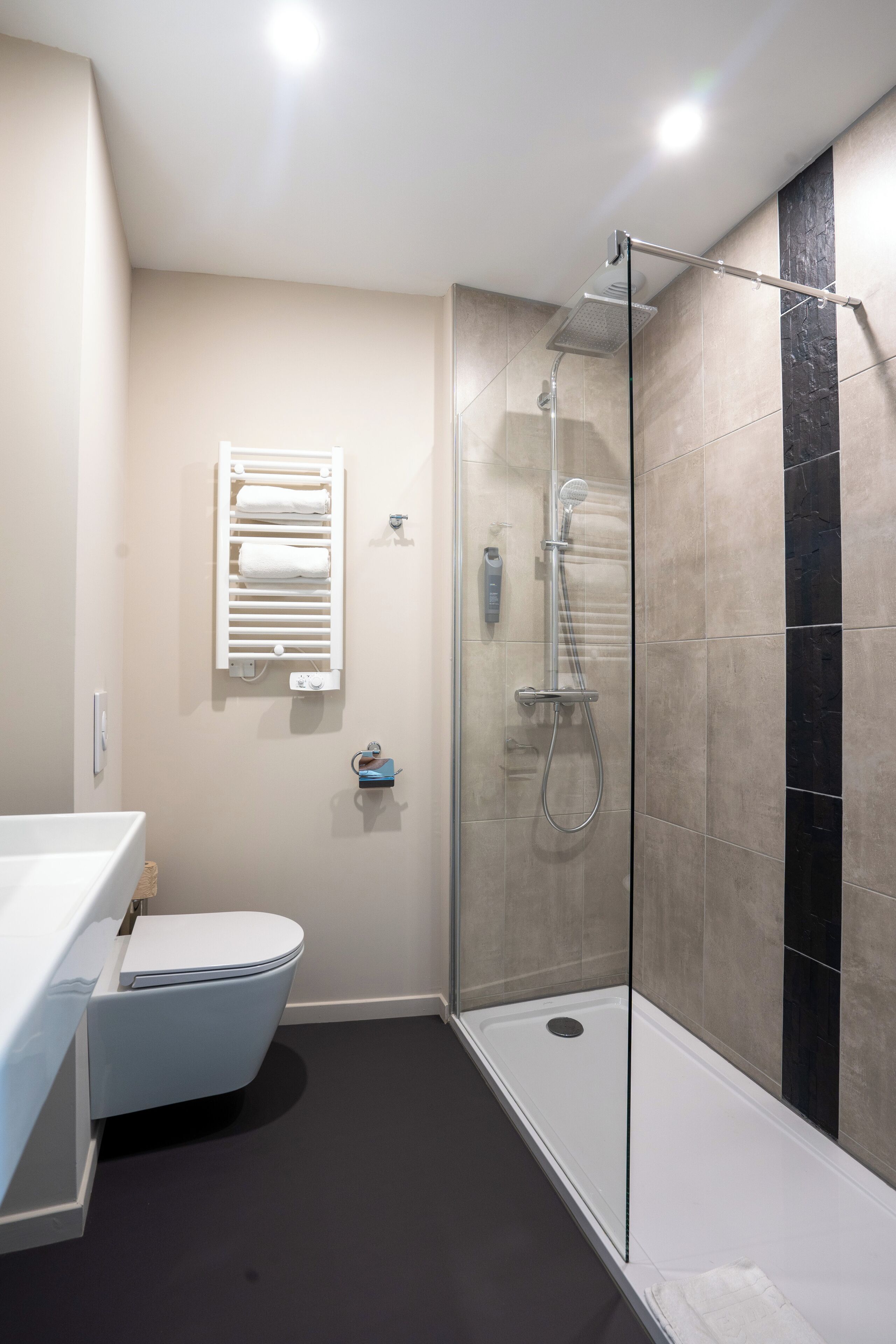 Un baño moderno con ducha de vidrio, inodoro y perchero para toallas.