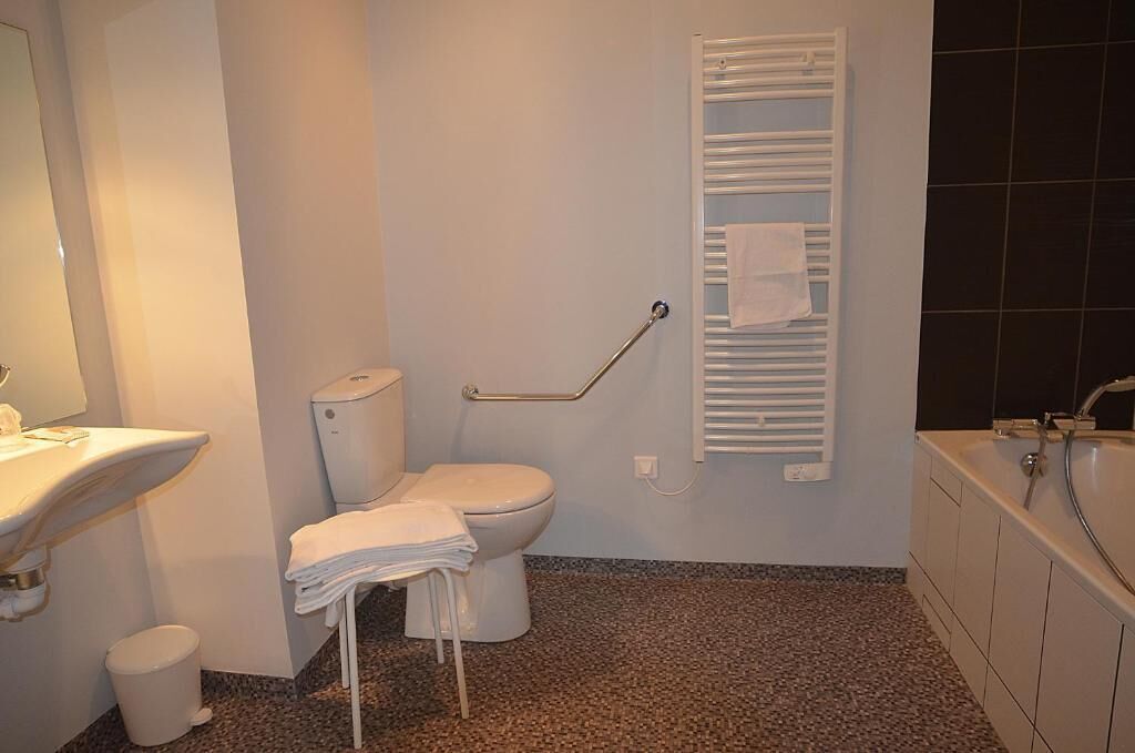 Un baño con inodoro, lavamanos, toallero y bañera.
