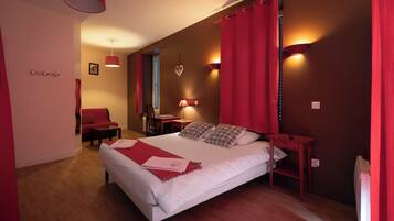 A bedroom with a large bed, red curtains, a desk, and a chair.