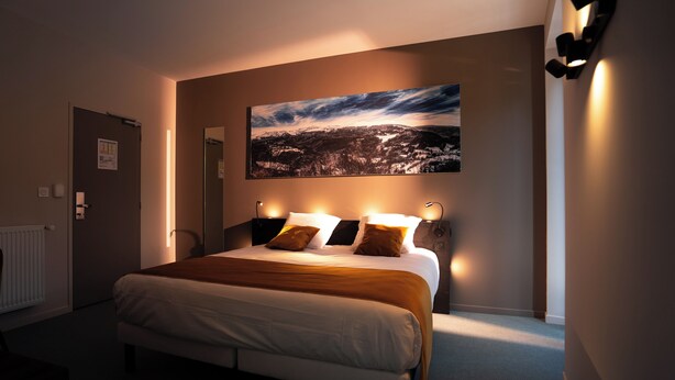 Een hotelkamer met een groot bed, een schilderij aan de muur en uitzicht op een stadsbeeld.