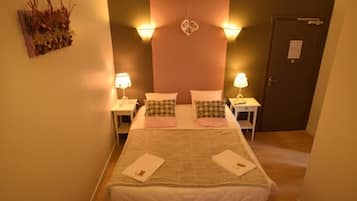 Een hotelkamer met een bed, twee nachtkastjes, een decoratief wandobject en een deur.