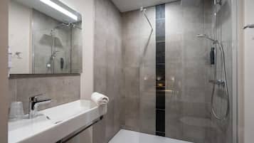 A modern bathroom with a glass-enclosed shower, a white sink, and a mirror above it.