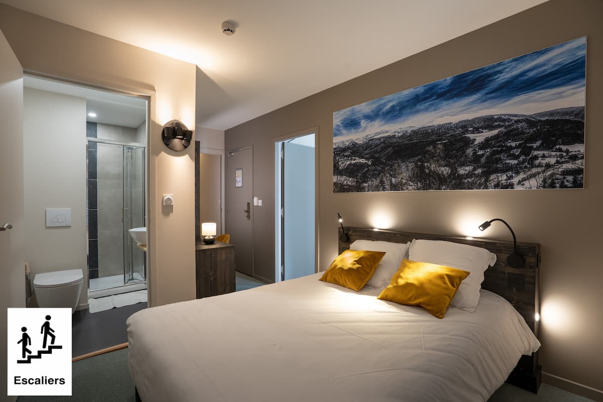 Ein Hotelzimmer mit Bett, einem Bild und einem Badezimmer mit Dusche und Toilette.
