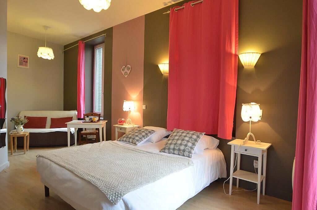 Une chambre à coucher avec un lit, des tables de chevet, une commode, une fenêtre et un rideau rouge.