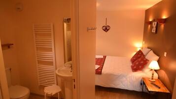A small, cozy bedroom with a single bed, bedside table, and a nightstand.