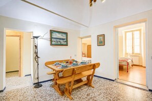 A dining area with a wooden table and bench, a floor lamp, and framed artwork on the walls.