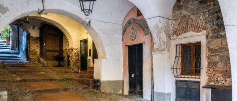 A stone staircase leading to a door with a number sign, an arched doorway, and a lantern hanging from the ceiling.