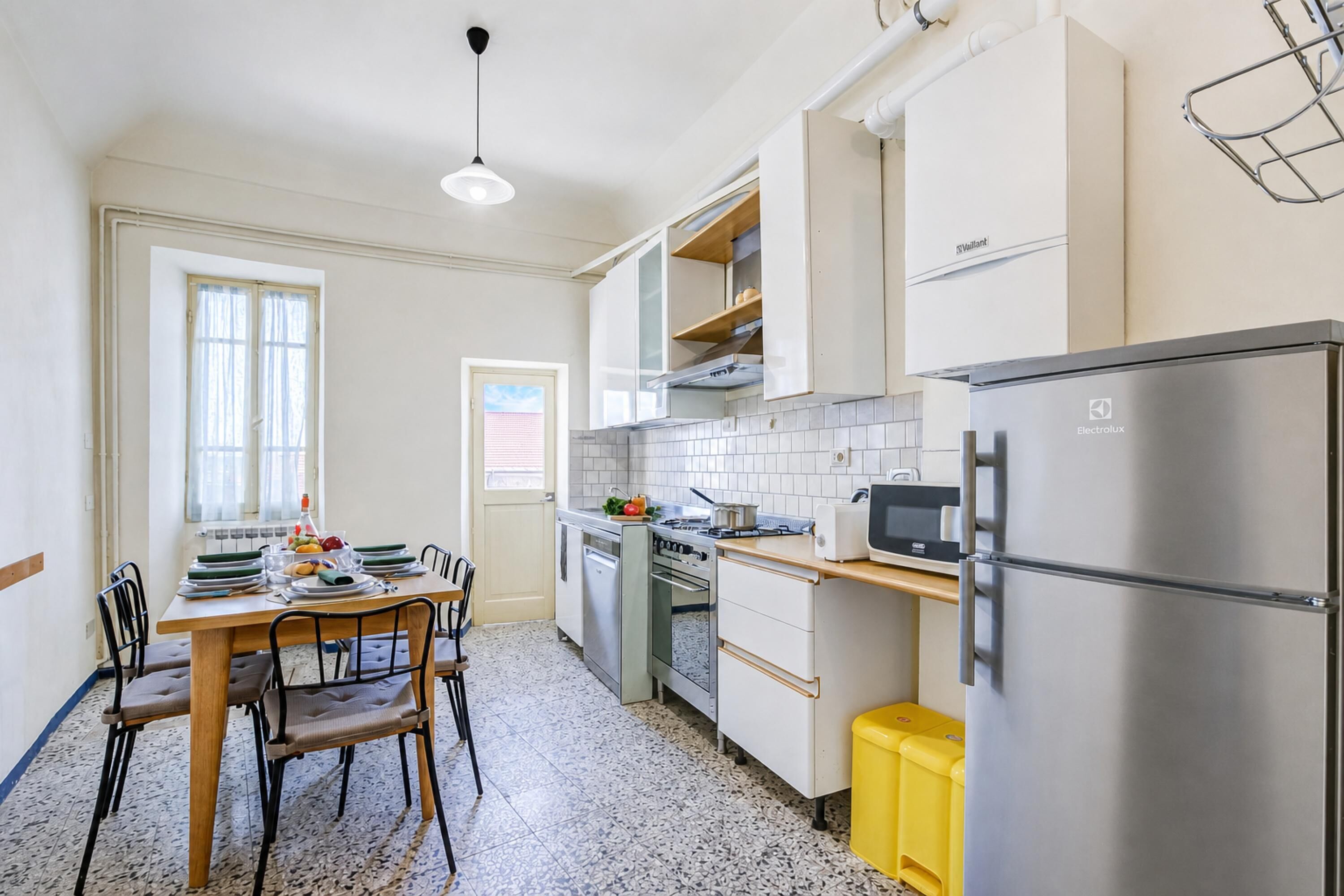 Une cuisine compacte comprenant une table à manger, des chaises, un réfrigérateur, un four à micro-ondes et une cuisinière.