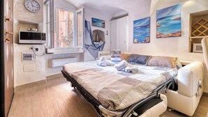 Un dormitorio con cama, silla de ruedas, microondas, reloj y obras de arte en las paredes.