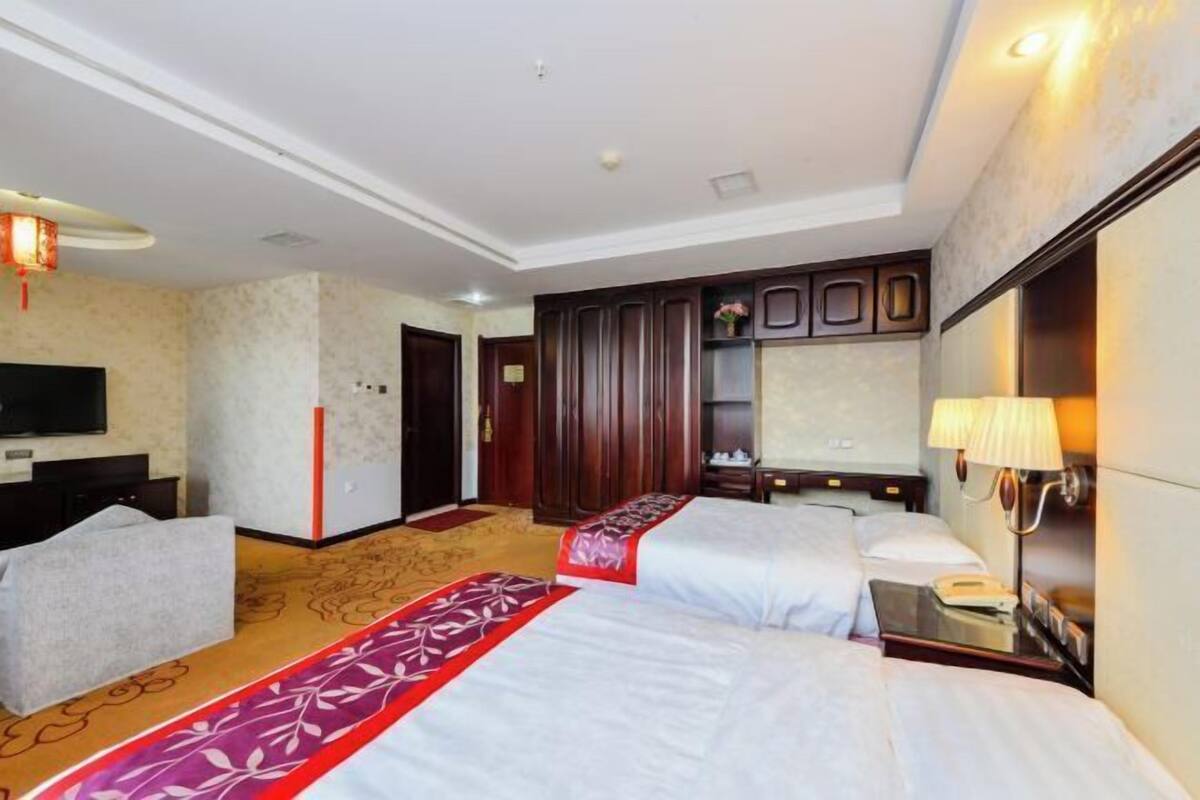 Une chambre d’hôtel avec deux lits, une télévision, un bureau et une armoire.