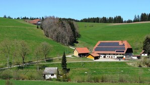 A rural setting with a large building featuring a solar panel roof, surrounded by green fields and trees. - Historic Retreat, St. Georgen (Sankt Georgen im Schwarzwald)