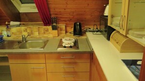 A compact kitchen with a sink, stove, and wooden cabinets. - Historic Retreat, St. Georgen (Sankt Georgen im Schwarzwald)