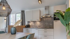 A modern kitchen with white cabinets, a marble backsplash, and a built-in stove. - Chalet in Eindhoven Near Green Forests (Mierlo)
