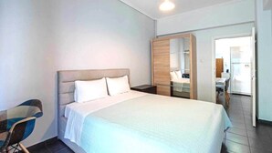A modern hotel room with a large bed, a wooden wardrobe, a desk, and a chair. - Perfect choice for your stay in central Athens (Athina)
