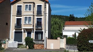 Un immeuble résidentiel à plusieurs étages, doté d’une façade symétrique, de nombreux balcons et d’une entrée sécurisée par un portail.