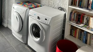 Un espace buanderie équipé de deux machines à laver à chargement frontal et d’une bibliothèque remplie de livres.