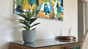 A room with a potted plant on a textured surface, a wall-mounted abstract painting, and a small wooden object on the right. - Hope Winds - by Zenbreak (Providence)