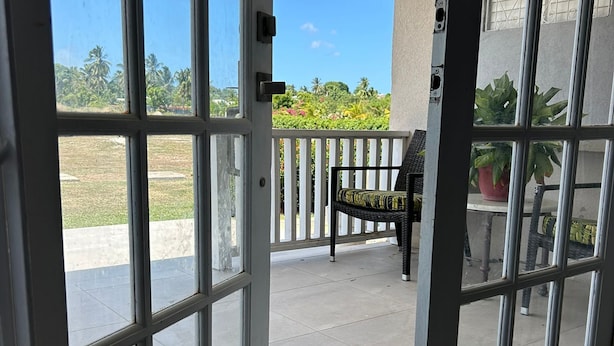 A view through a glass door leading to an outdoor patio area with a bench and potted plants. - Hope Winds - by Zenbreak (Providence)
