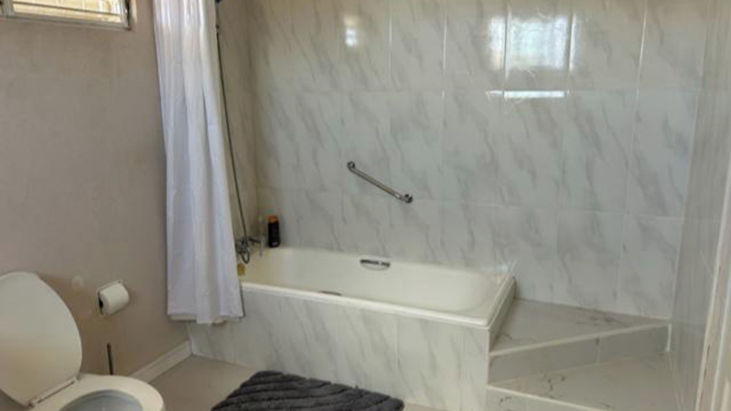 A bathroom with a toilet, a bathtub, and a shower area.