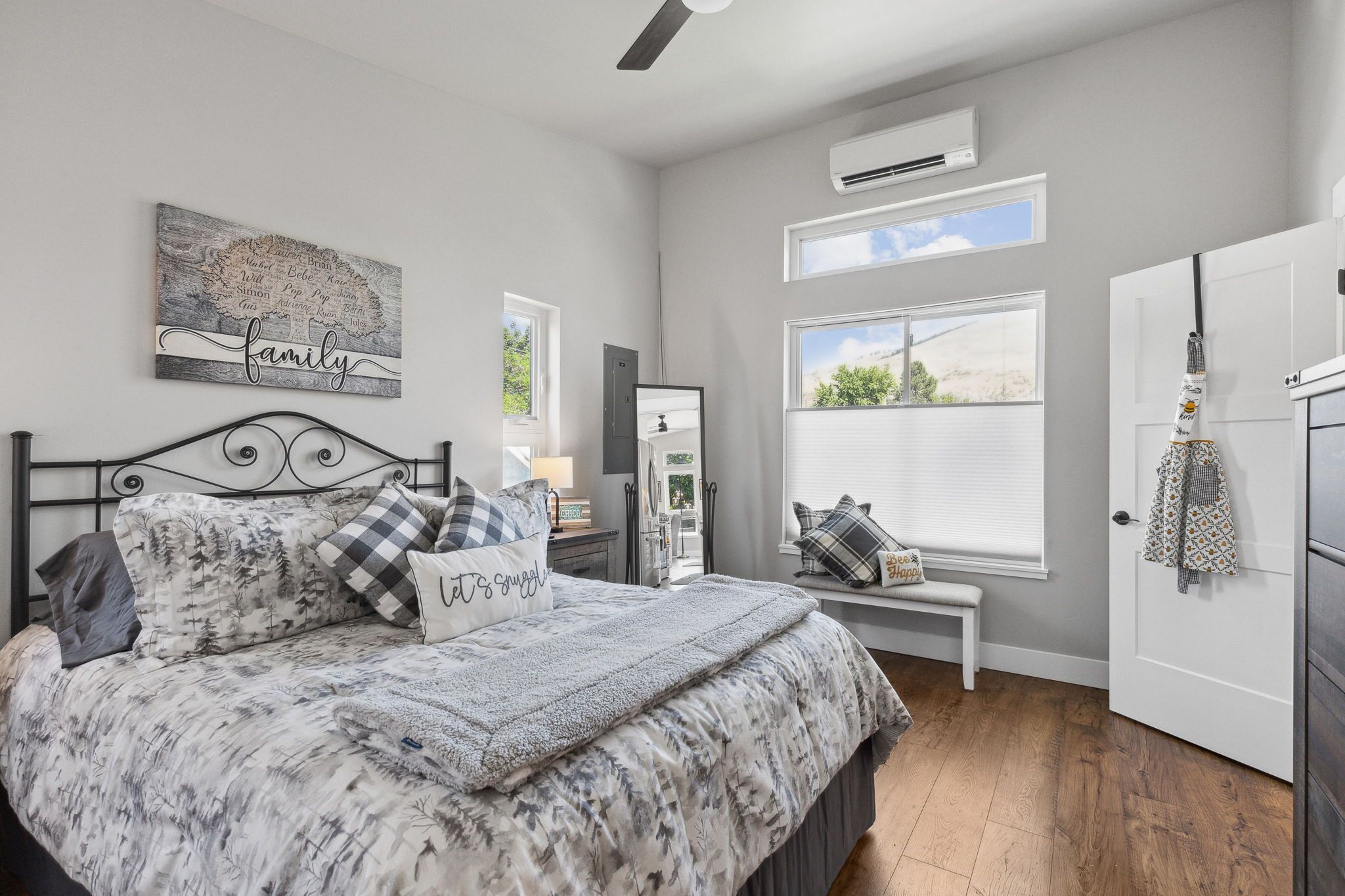 A bedroom with a bed, a bench, a window, and a door.