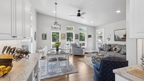 Een ruime woonkamer met een eettafel, een bank en een plafondventilator.