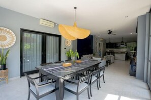 A spacious dining area with a long table, chairs, and a hanging light fixture. - Namaya Villa Senggigi by The Lavana (West Lombok Regency)