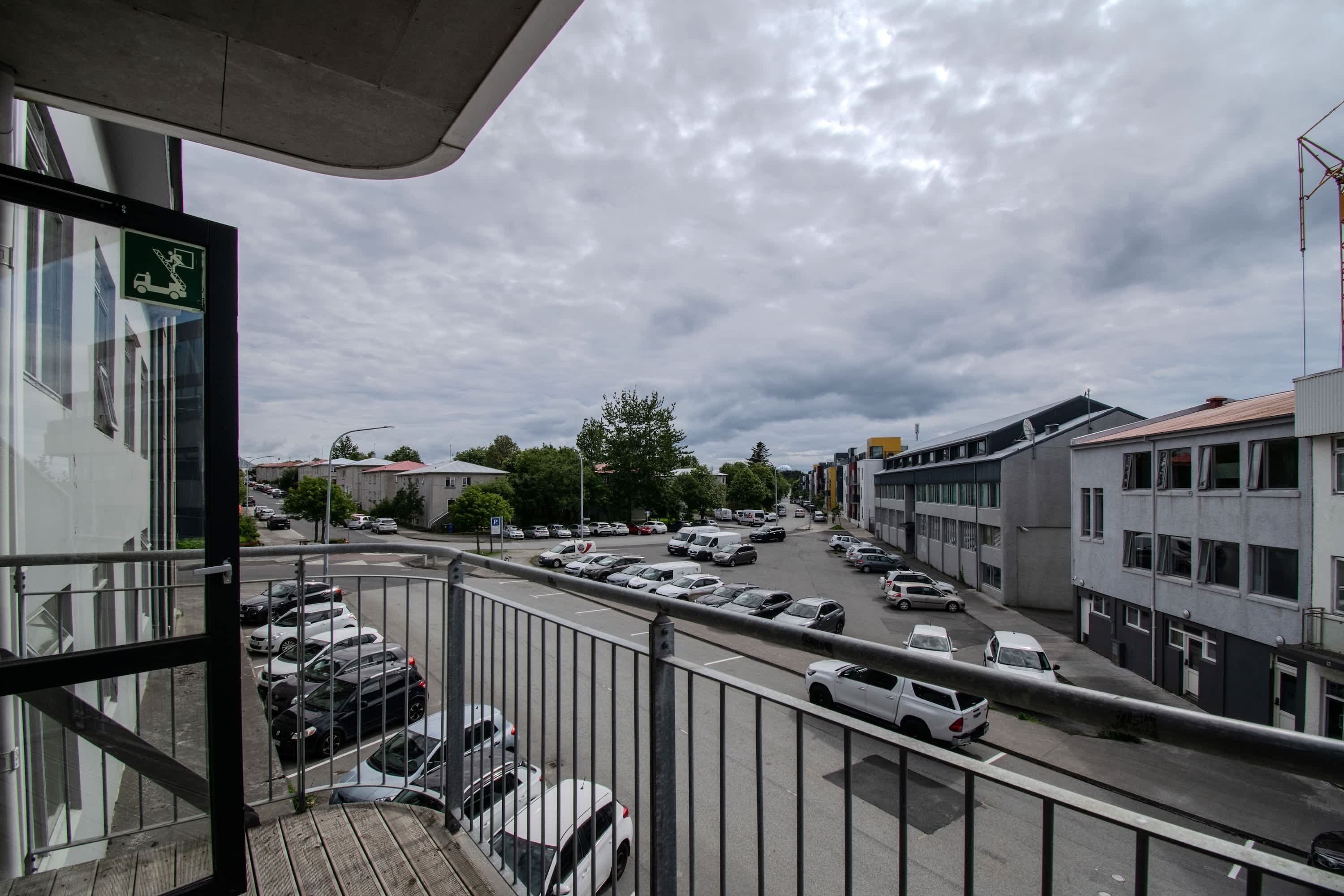 A view from a balcony overlooking a parking lot with cars and buildings.