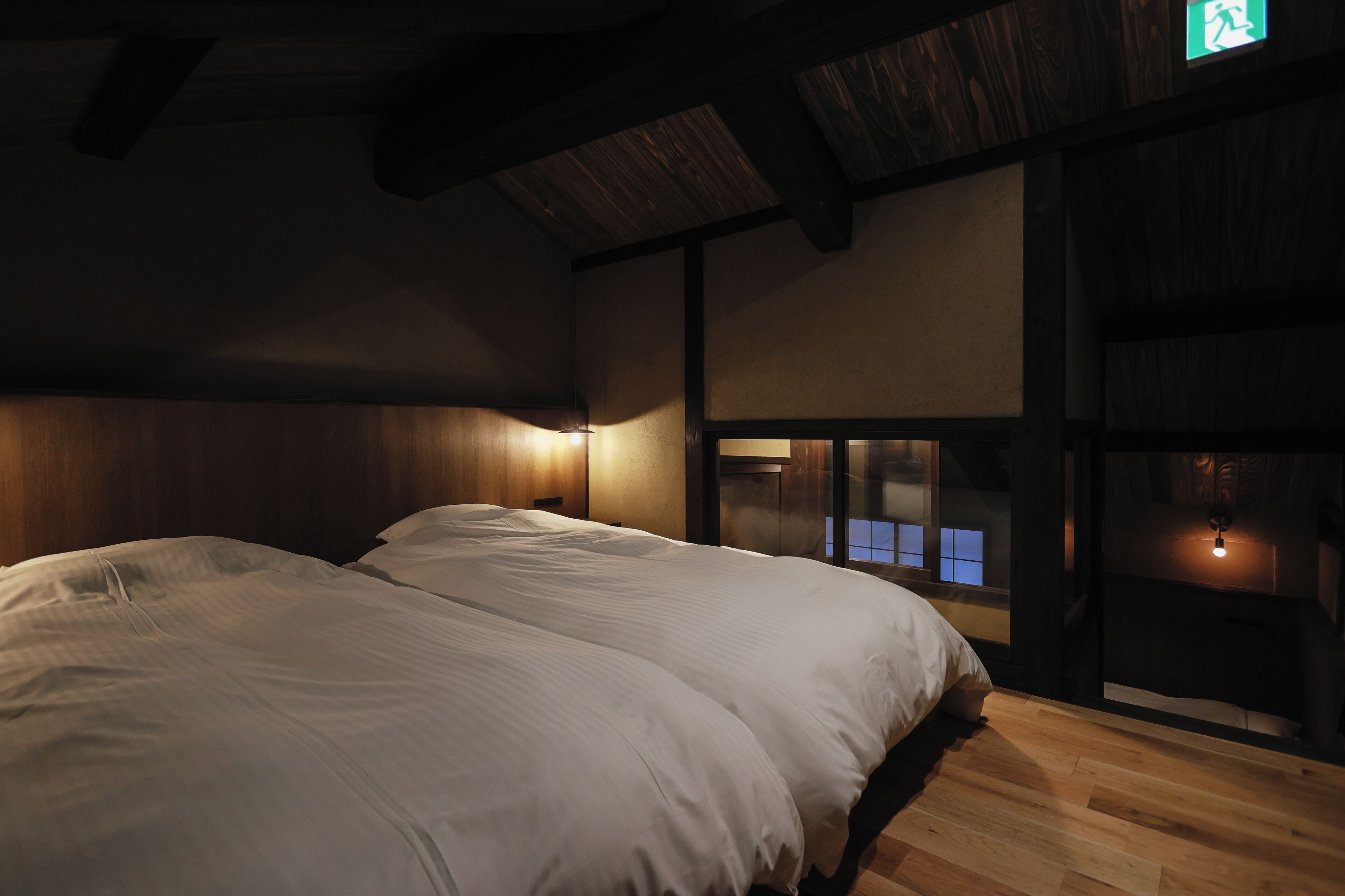 Una habitación con una cama grande, vigas de madera en el techo y vistas por una ventana.