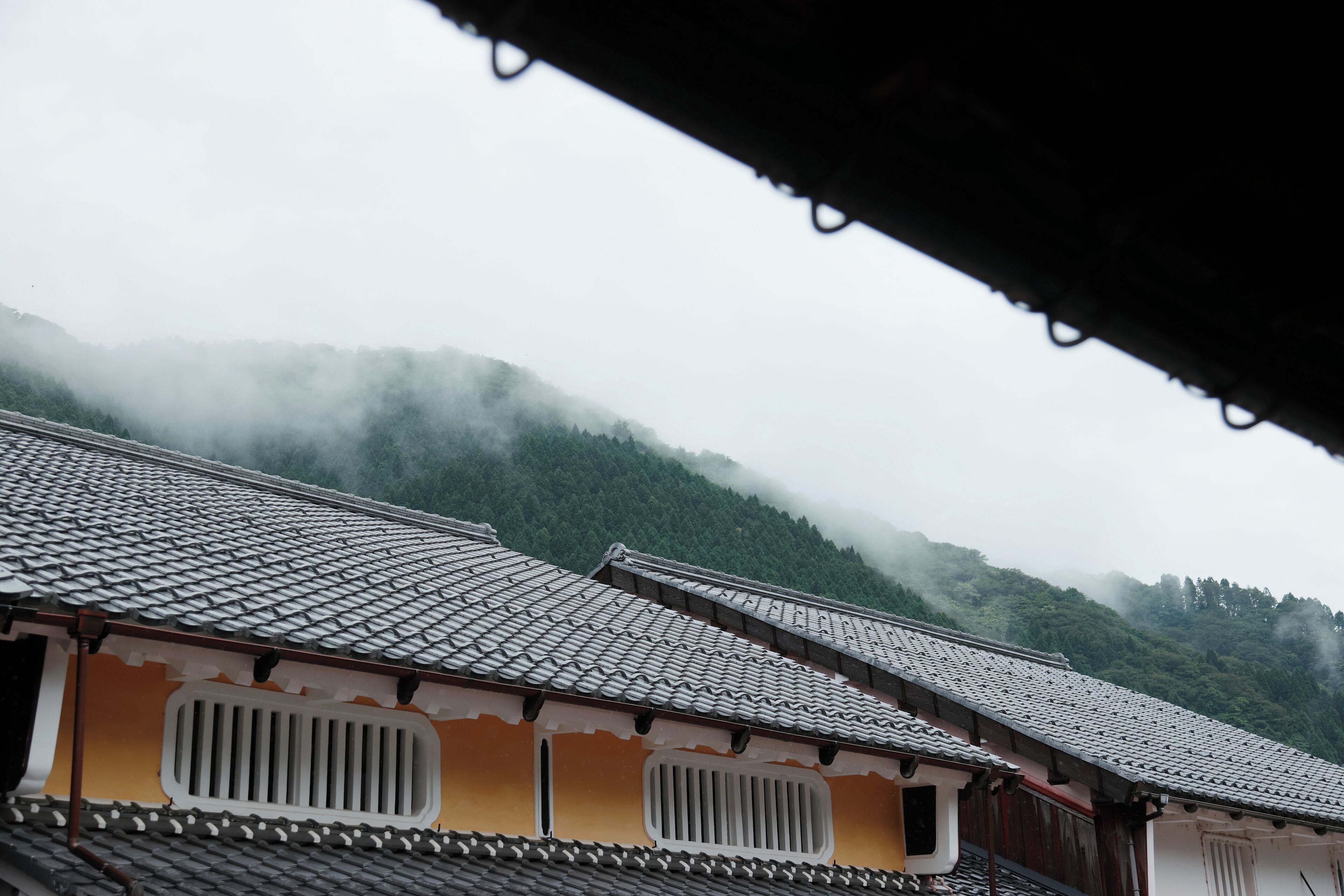 Un bâtiment traditionnel, doté d’un toit en tuiles et situé dans un cadre montagneux.
