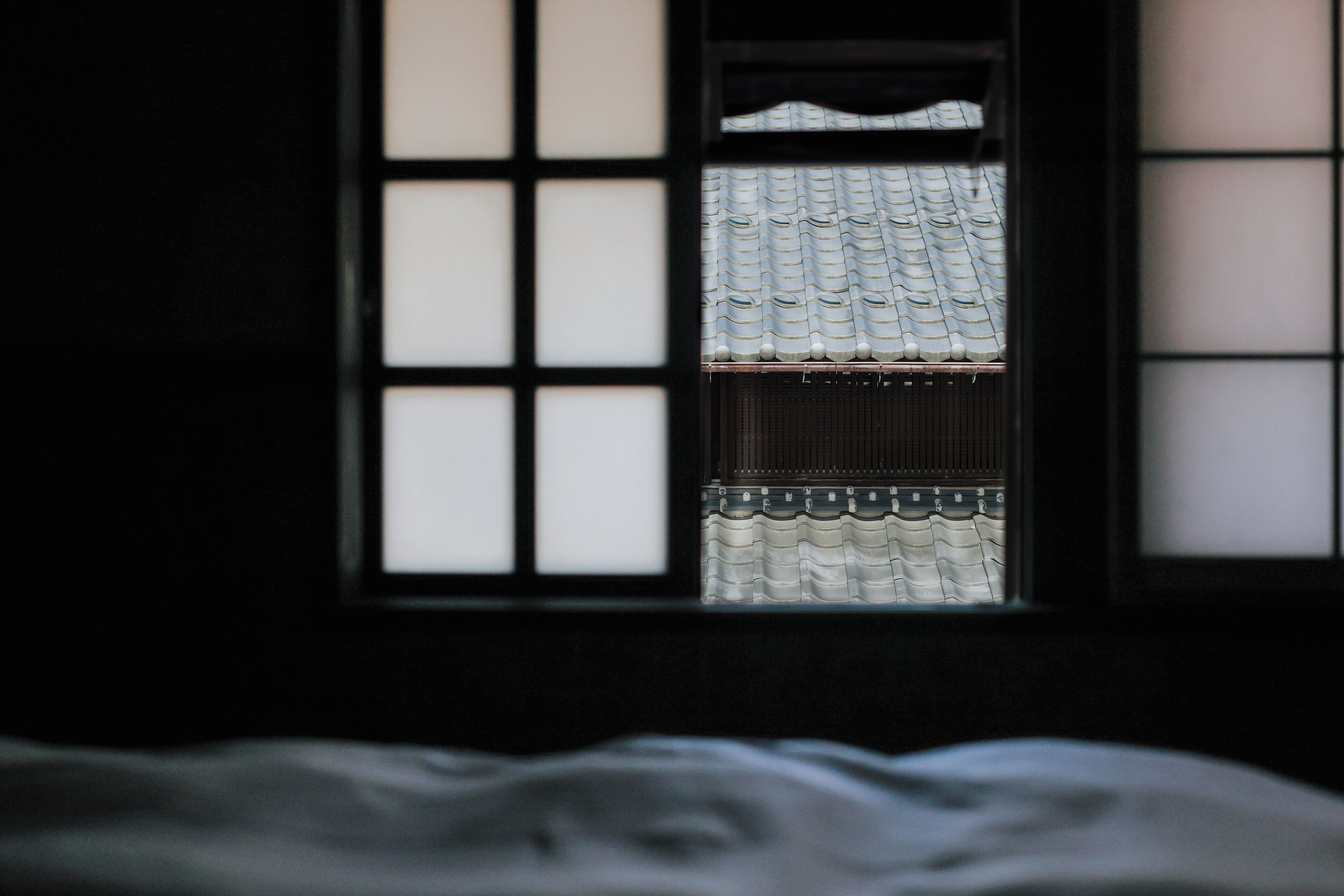 A room with a window revealing a traditional tiled roof outside.
