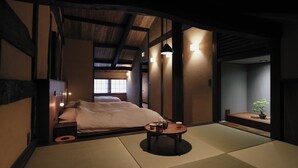 A traditional Japanese-style room with tatami flooring, a bed with white bedding, a small table with a plant, and wall-mounted lighting. - 八百熊川 Yao-Kumagawa (Wakasa)