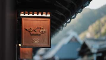 A wooden sign with Japanese characters, mounted on a building with a traditional roof.