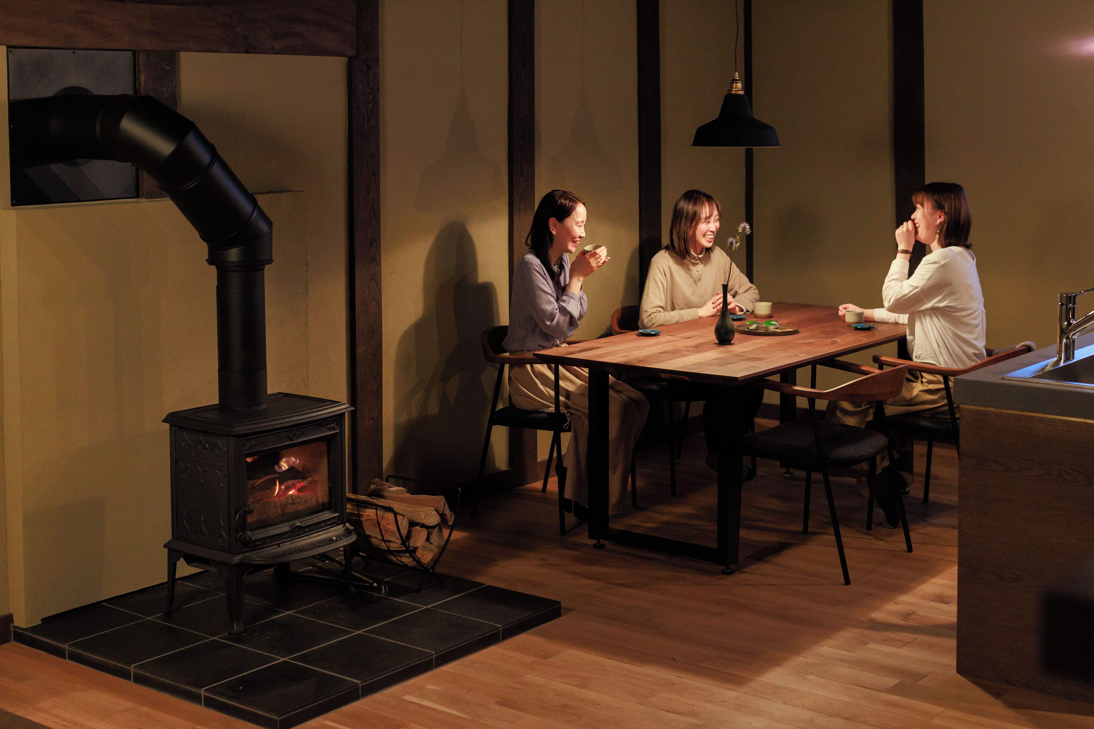 A cozy dining area with a wood-burning stove, a wooden table, and chairs.