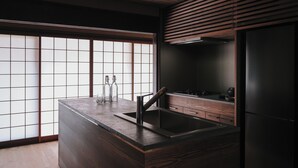 A modern kitchen with a wooden countertop, a sink, and a built-in stove. - 八百熊川 Yao-Kumagawa (Wakasa)