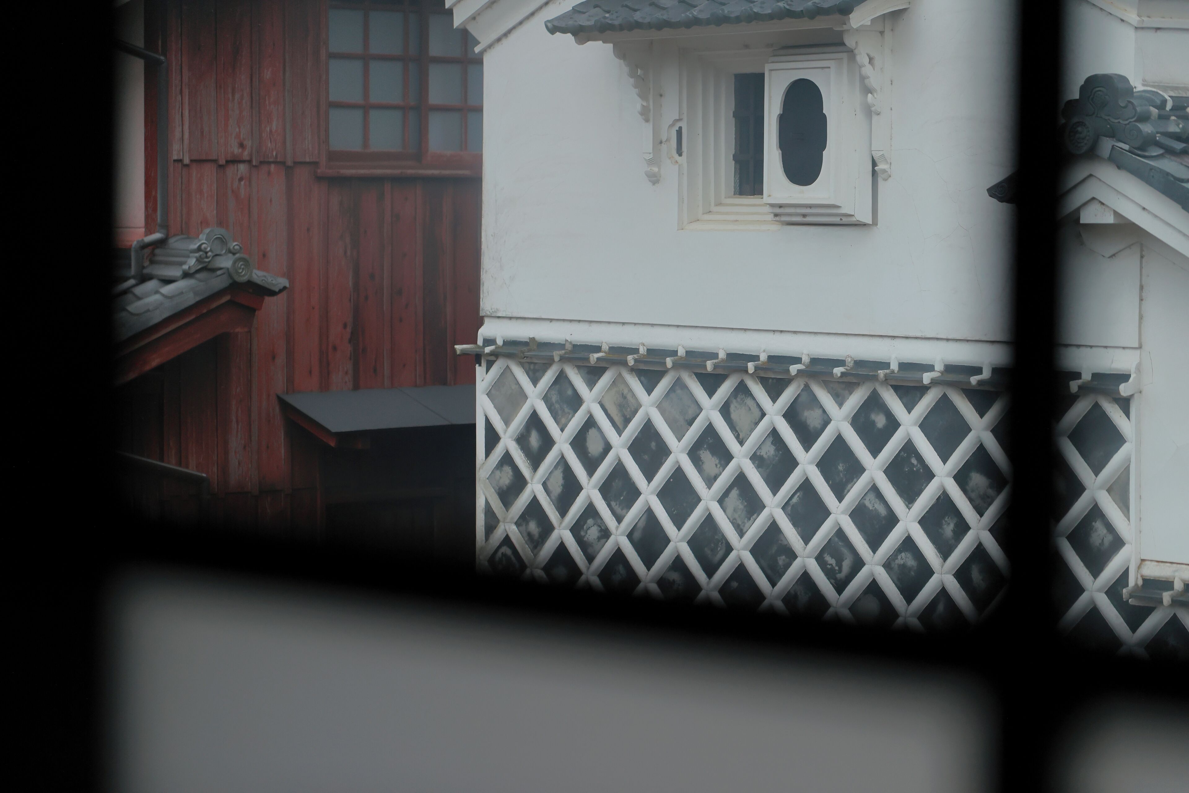 A white building with a lattice fence, a wooden door, and a window with a decorative frame.