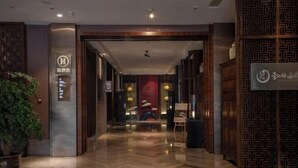A hotel lobby with a polished wooden floor, a reception desk, and a decorative wall with a traditional pattern. - Jinke Saint Hotel (Wuxi)
