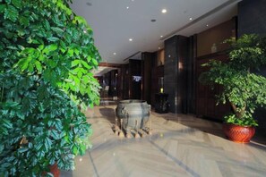 A corridor with a potted plant on the left and a large decorative urn on the right. - Jinke Saint Hotel (Wuxi)