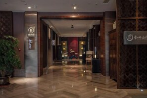 A hotel lobby with a polished wooden floor, a reception desk, and a large potted plant. - Jinke Saint Hotel (Wuxi)