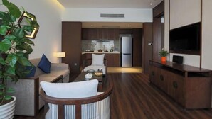 A modern living room with a sofa, a dining table, and a kitchen in the background. - Jinke Saint Hotel (Wuxi)