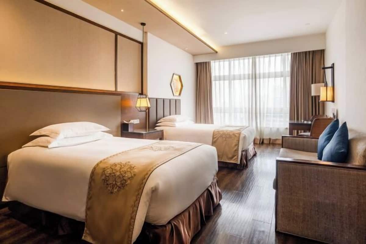 Habitación de hotel con dos camas, un escritorio y una silla.