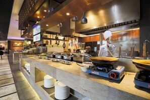 A modern kitchen with a chef preparing food, a buffet setup with various dishes, and a clean, well-lit environment. - Jinke Saint Hotel (Wuxi)