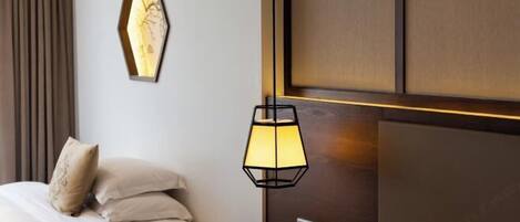 A hotel room with a bed, a nightstand, a lamp, and a wall-mounted artwork.