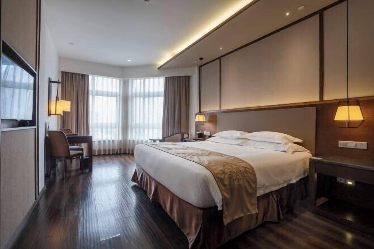 Habitación de hotel con una cama grande, un escritorio y dos lámparas.