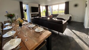 A modern living room with a dining area, a sofa, a TV, and a view of the outdoors. - Modern Eco-villa Near the Veluwemeer (Biddinghuizen)