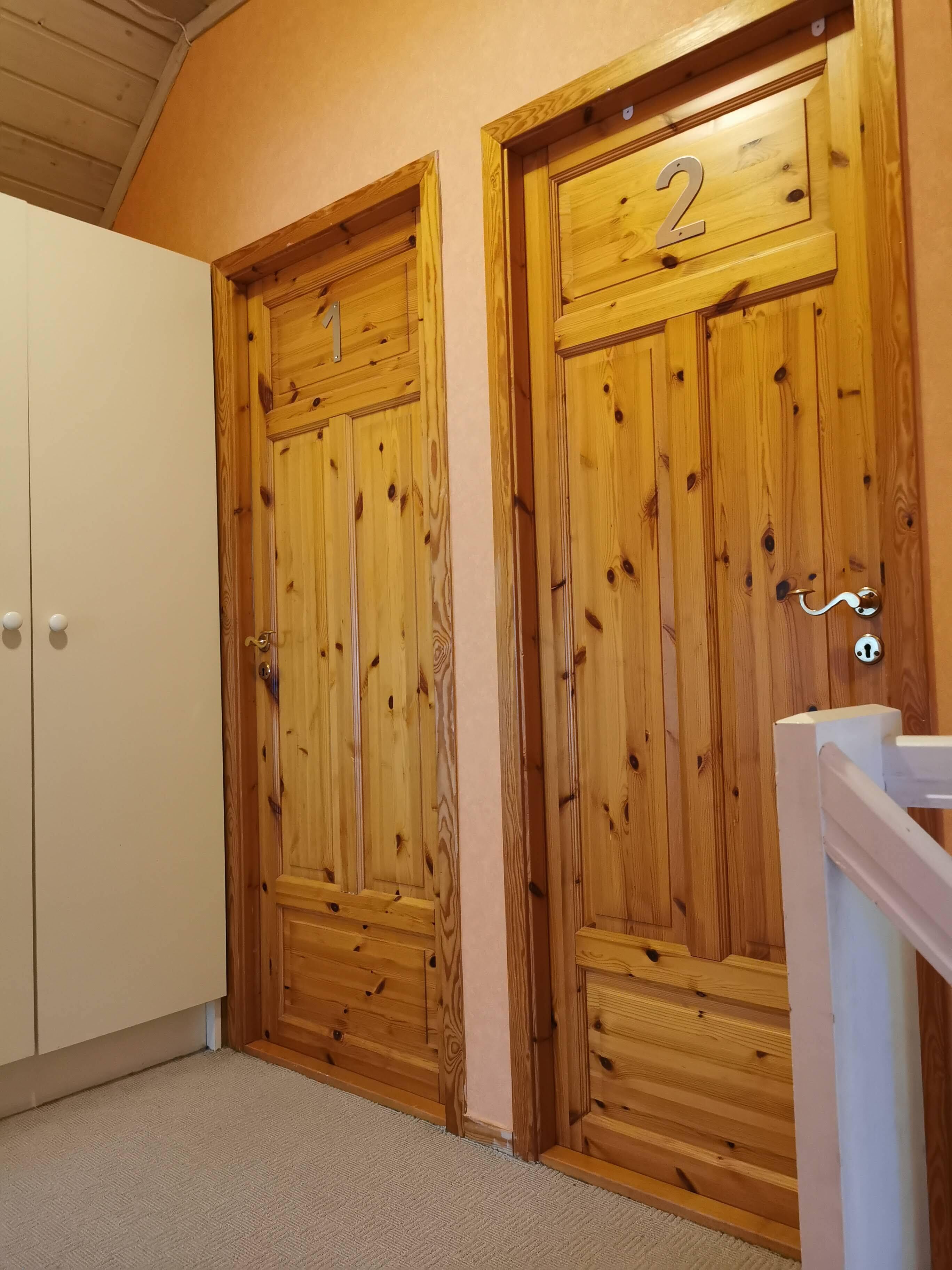 Two wooden doors with numbers, a white cabinet, and a white railing.