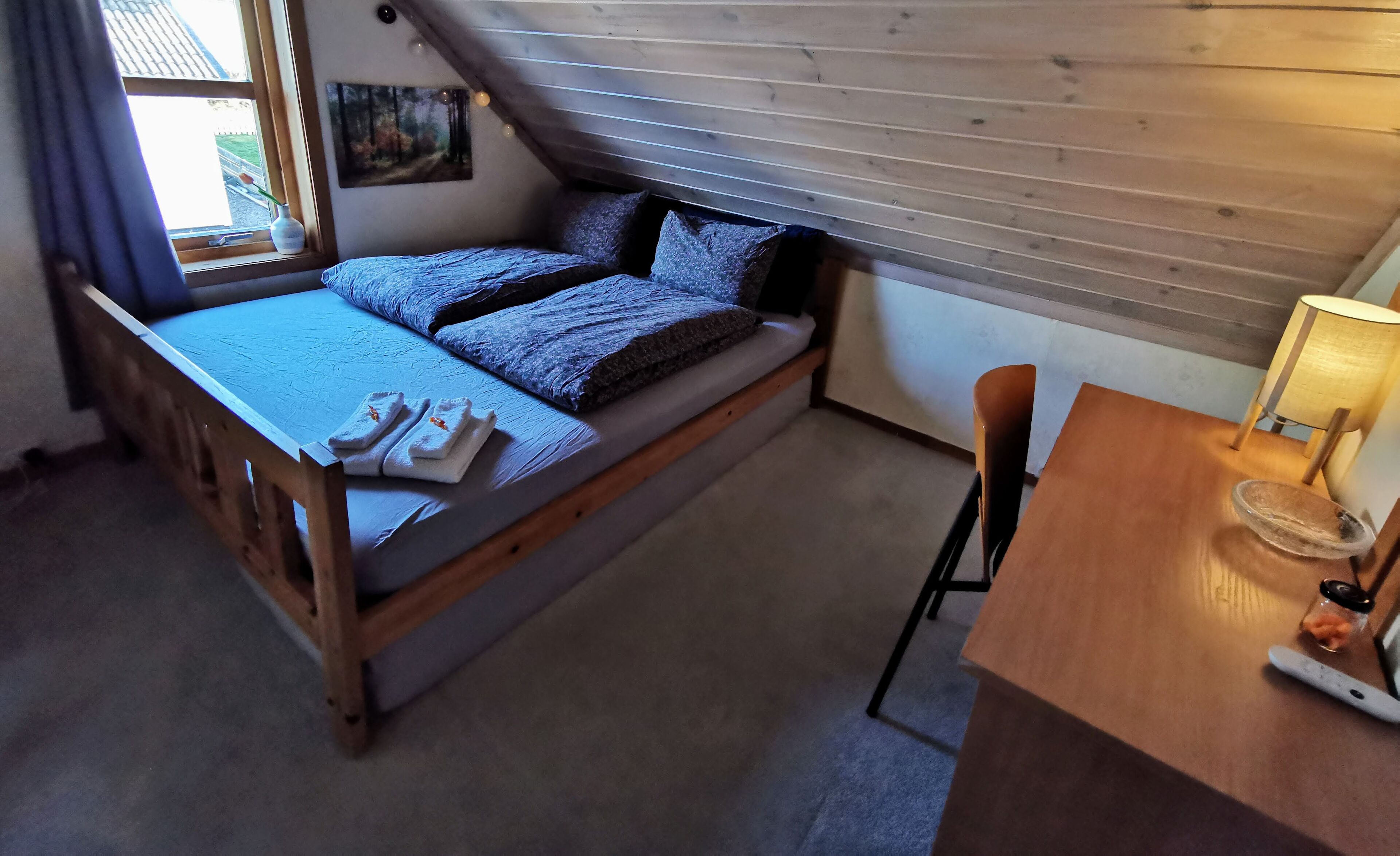 A cozy bedroom with a loft bed, a small desk, and a chair.