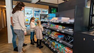 A store interior with shelves stocked with various products, a refrigerated display, and a black cabinet.
